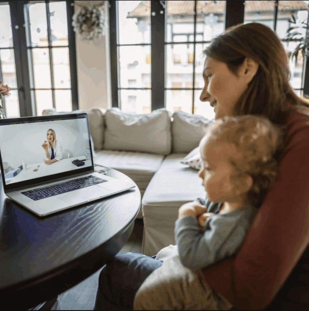 A woman video chats on a laptop while holding a baby.